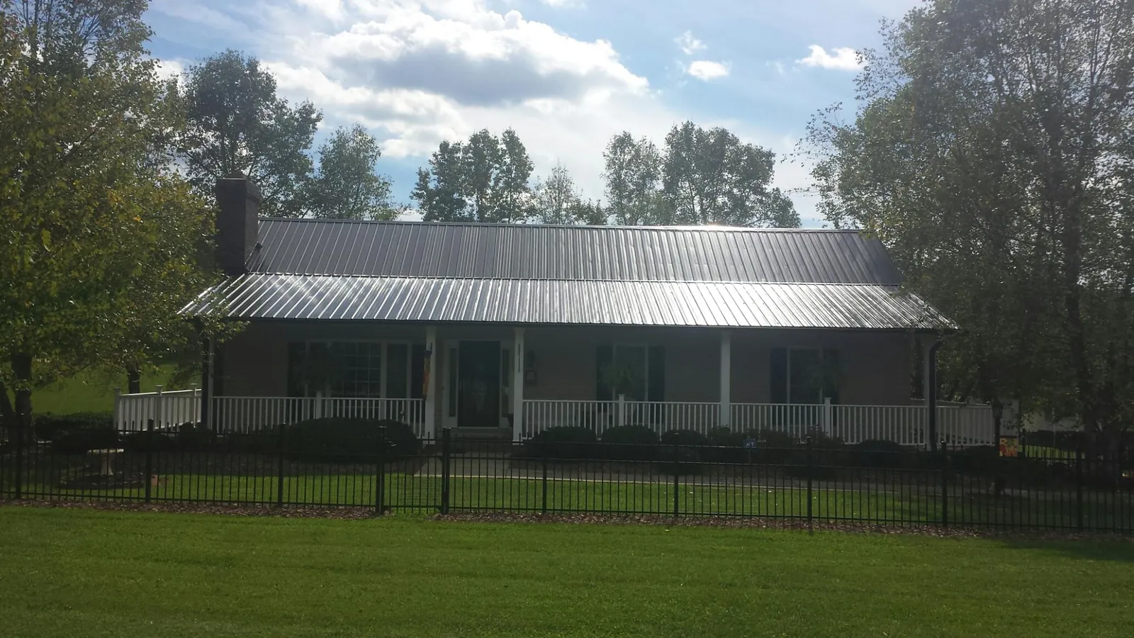 Gray metal roof on a brick ranch with a full width front porch — Gutter Guard Installation work by our crew in Cornelius