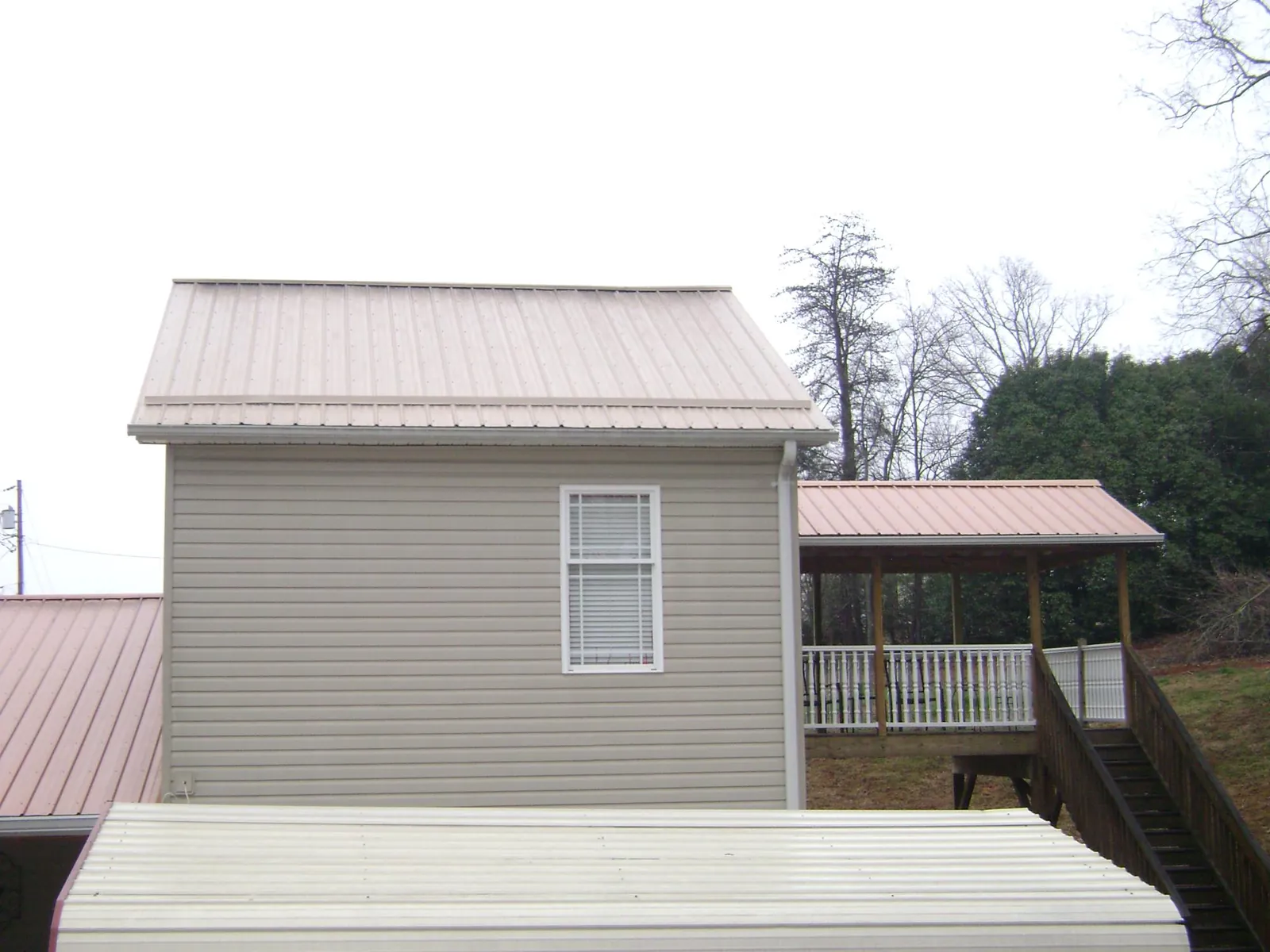 Tan metal roofs on a two story addition and attached porch in Cornelius