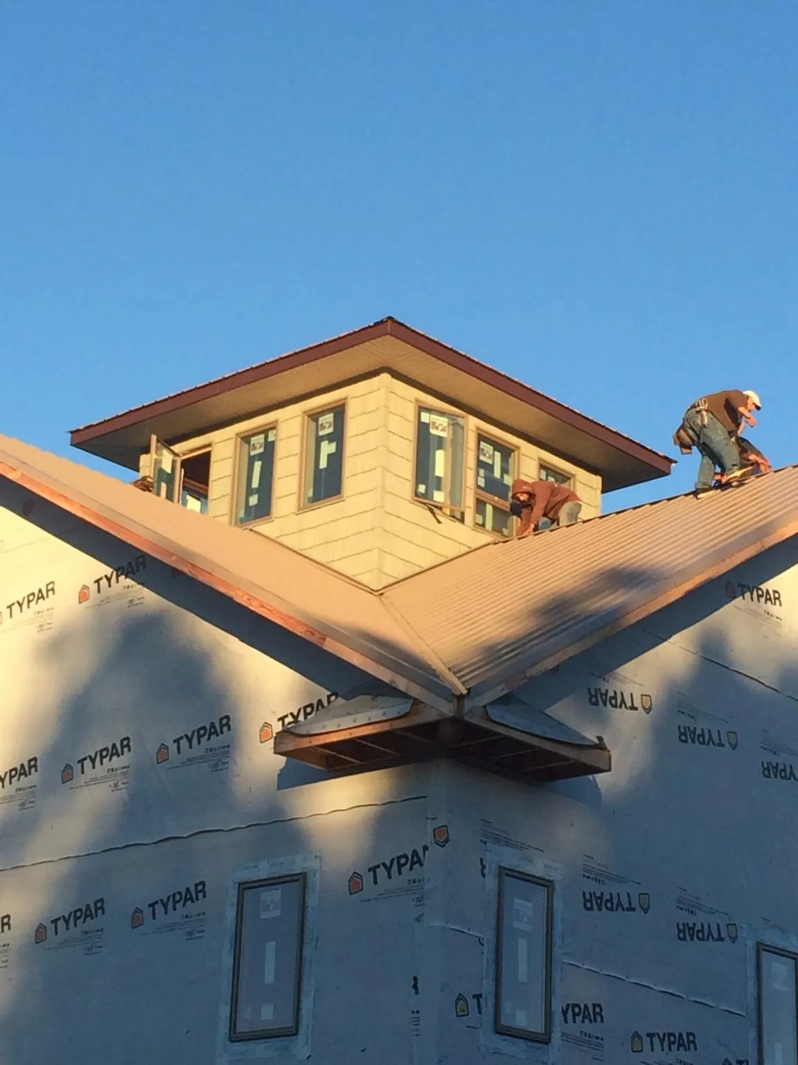 Roofers working around a rooftop cupola on a new metal roof at sunset — Roof Waterproofing in Cornelius by Roofing Brothers